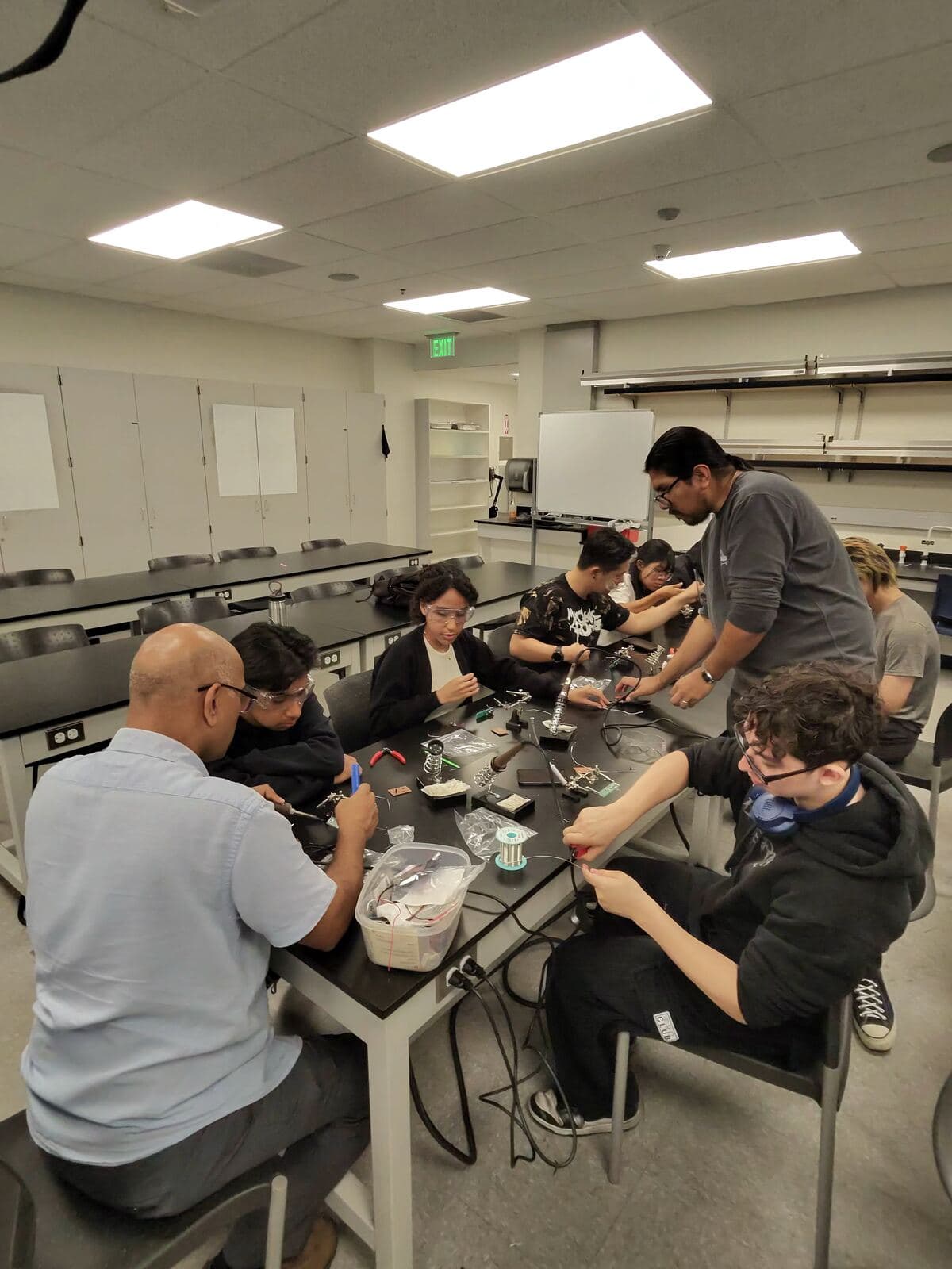 Members soldering and assembling electronics at a lab table